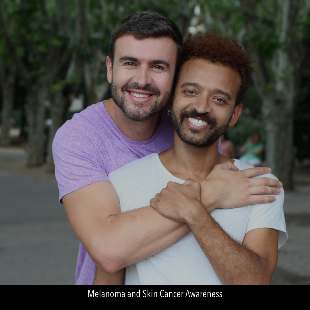 Image of male gay couple in an embrace and smiling at camera